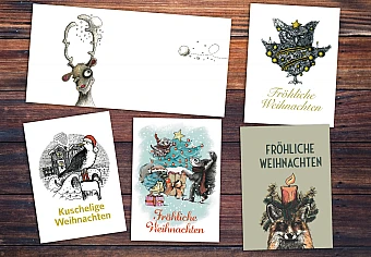 Fünf Weihnachtskarten mit verschiedenen Motiven auf einem Holztisch
