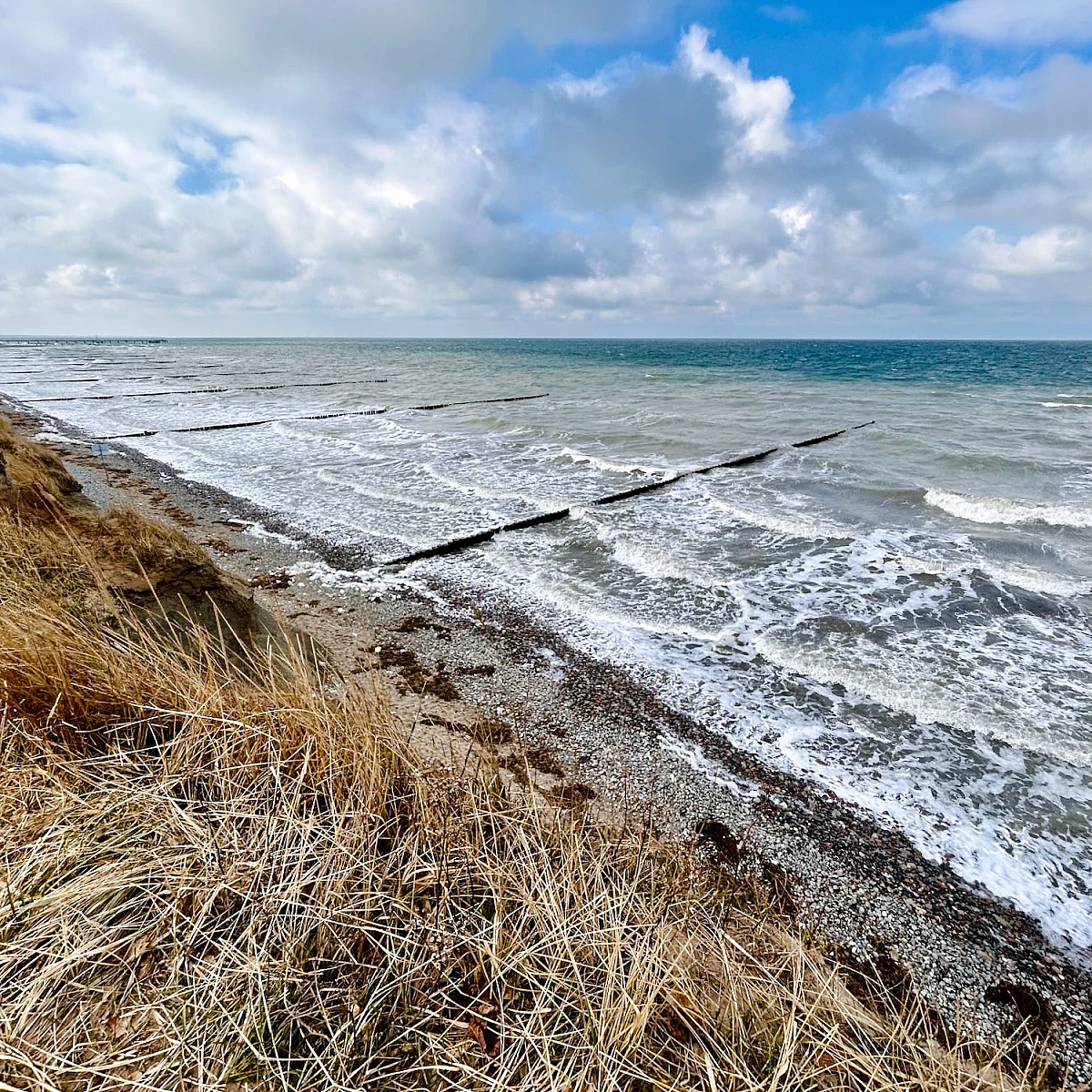 Im Vordergrund das Hohe Ufer im Hintergrund das stürmische Meer.