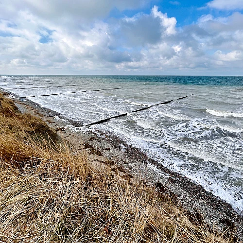 Im Vordergrund das Hohe Ufer im Hintergrund das stürmische Meer.