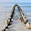 Frontaler Blick auf eine zweigeteilte Buhne, die in die Ostsee ragt.