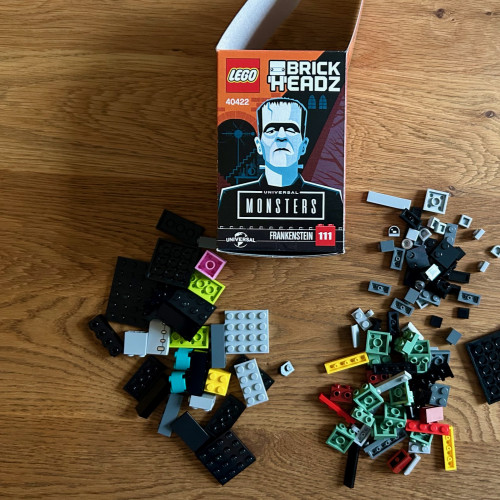 Auf einem Holztisch liegen verschiedene Legosteine sowie die Verpackung