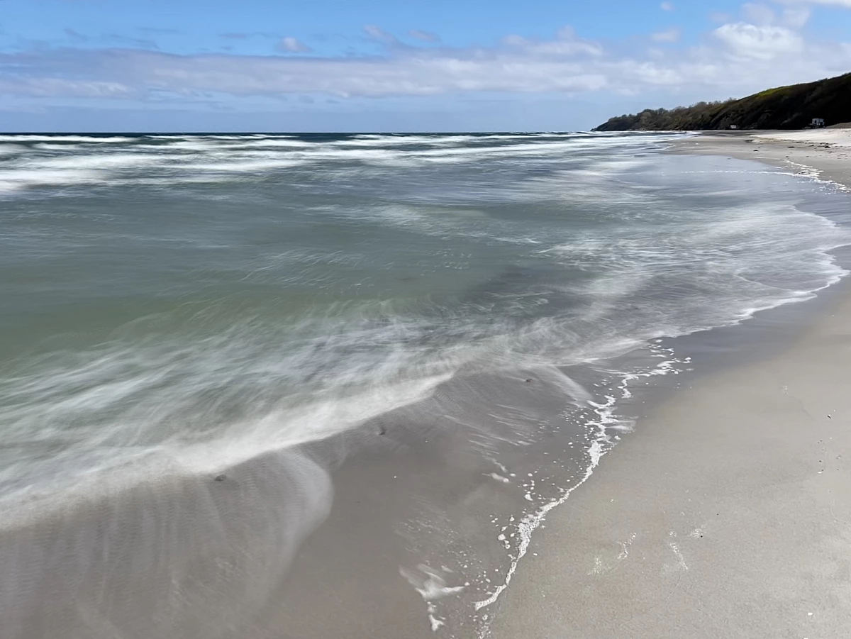 Im Mittelpunkt liegen mehrere große Steinen am Strand und in der Ostsee. Das Wasser drumherum ist durch Langzeitbelichtung verwaschen.