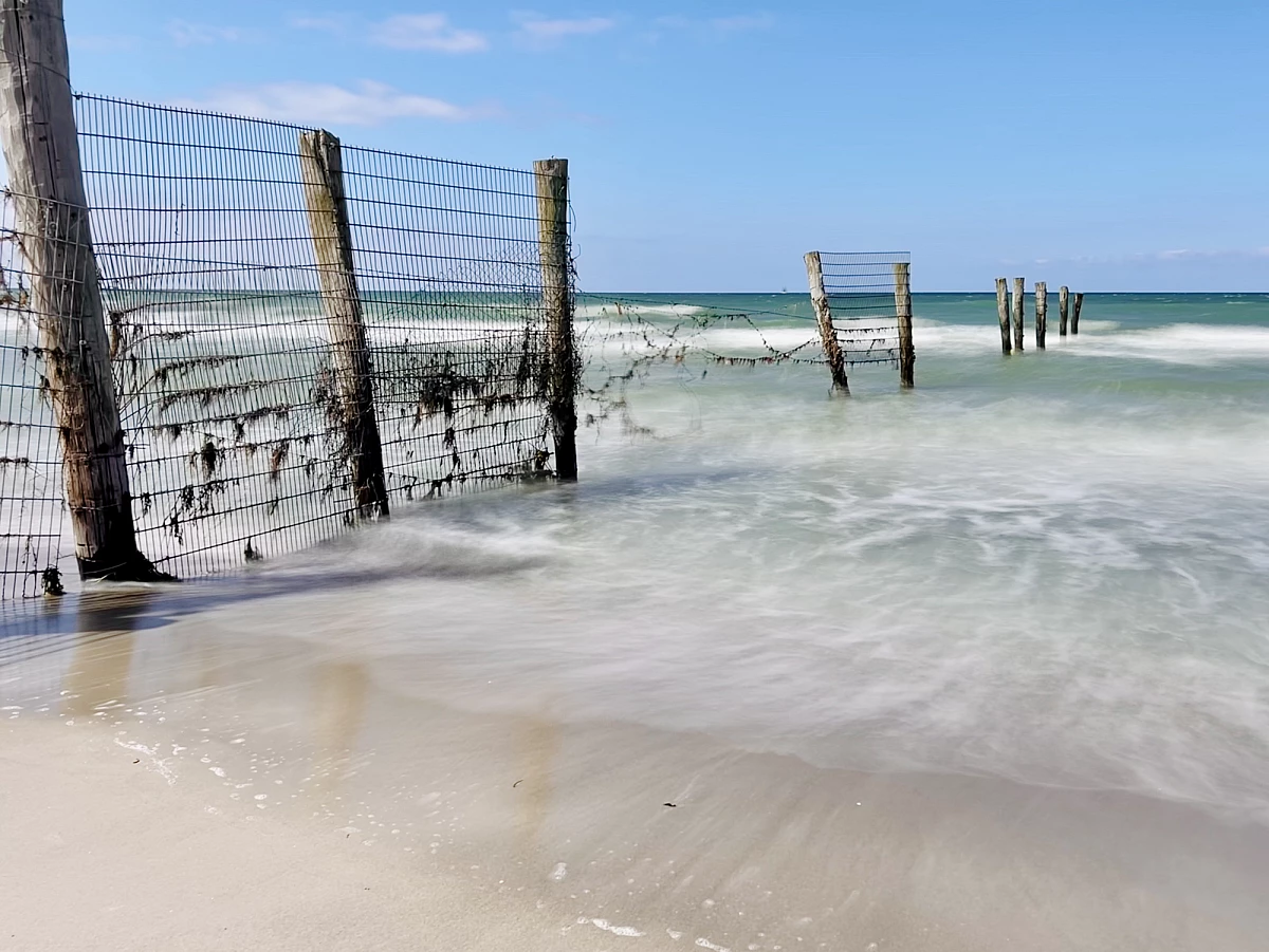 Im Mittelpunkt liegen mehrere große Steinen am Strand und in der Ostsee. Das Wasser drumherum ist durch Langzeitbelichtung verwaschen.