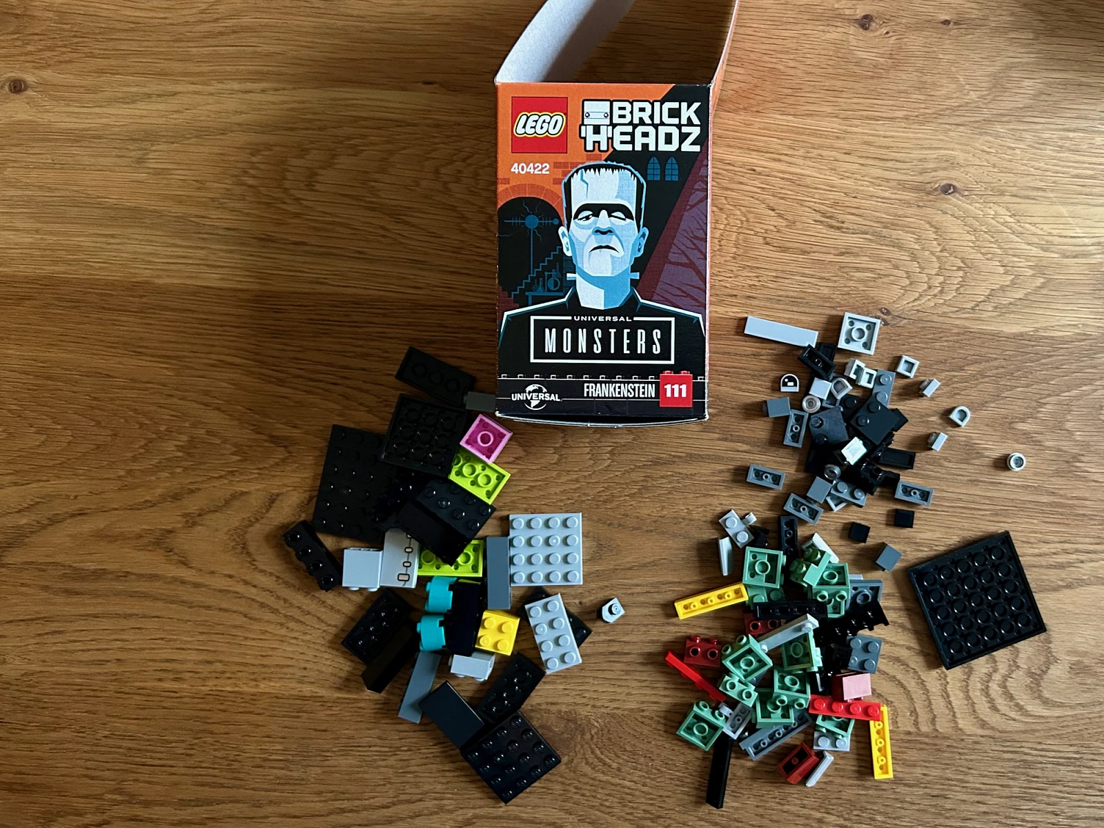 Auf einem Holztisch liegen verschiedene Legosteine sowie die Verpackung