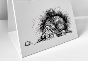 Der Kalender steht aufgeklappt auf einer weißen Fläche. Es ist der Monat Februar zu sehen. Es ist eine Illustration zu sehen, auf der ein Eichhörnchen und zwei Haselnüsse in der Kindspose verweilen.