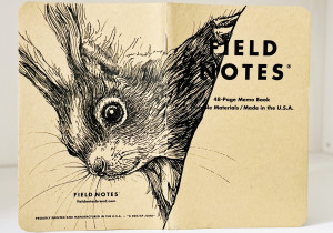 Ein aufgeklapptes Field Notes Heft auf dessen Rücken aus Kraft-Papier sich die schwarze Zeichnung eines Eichhörnchenkopfes erstreckt.