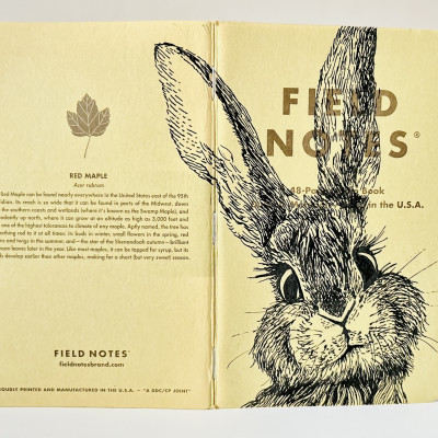 Auf dem Rücken des aufgeklappten Heftes ist eine schwarzweisse Tintenzeichnung eines Hasenkopfes zu sehen.