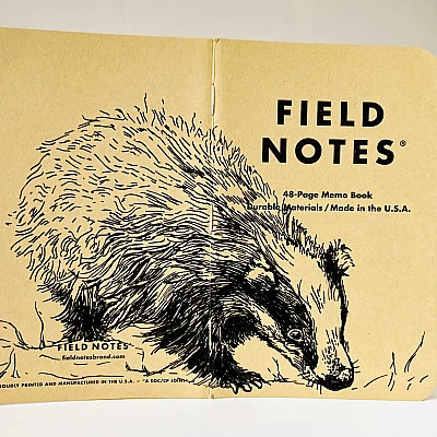 Ein aufgeklapptes Field Notes Heft auf dessen Rücken aus Kraft-Papier sich die schwarze Zeichnung eines Dachses befindet.