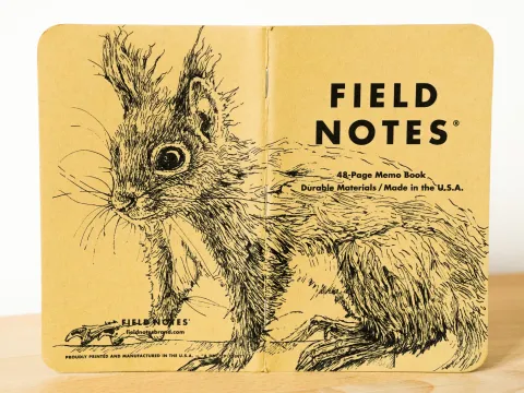 Ein aufgeklapptes Field Notes Heft auf dessen Rücken aus Kraft-Papier sich die Zeichnung eines Eichhörnchens befindet.