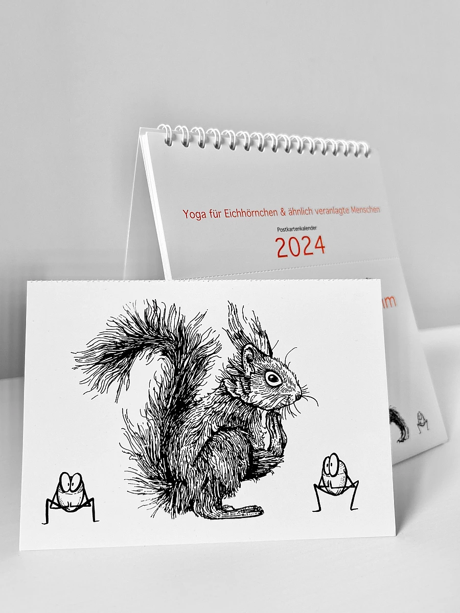 Der Kalender „Ommmmmmmmmmmm - Yoga für Eichhörnchen & ähnlich veranlagte Menschen - Postkartenkalender 2024" steht aufgeklappt auf einer weißen Fläche. Davor steht eine abgetrennte Postkarte. Die schwarze Illustration zeigt ein Eichhörnchen und zwei Haselnüsse in Squat-Pose.