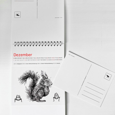 Der Kalender liegt flach auf dem Tisch, der Monat Dezember ist aufgeklappt. Daneben liegt eine eine abgetrennte Postkarte aus dem Kalender.